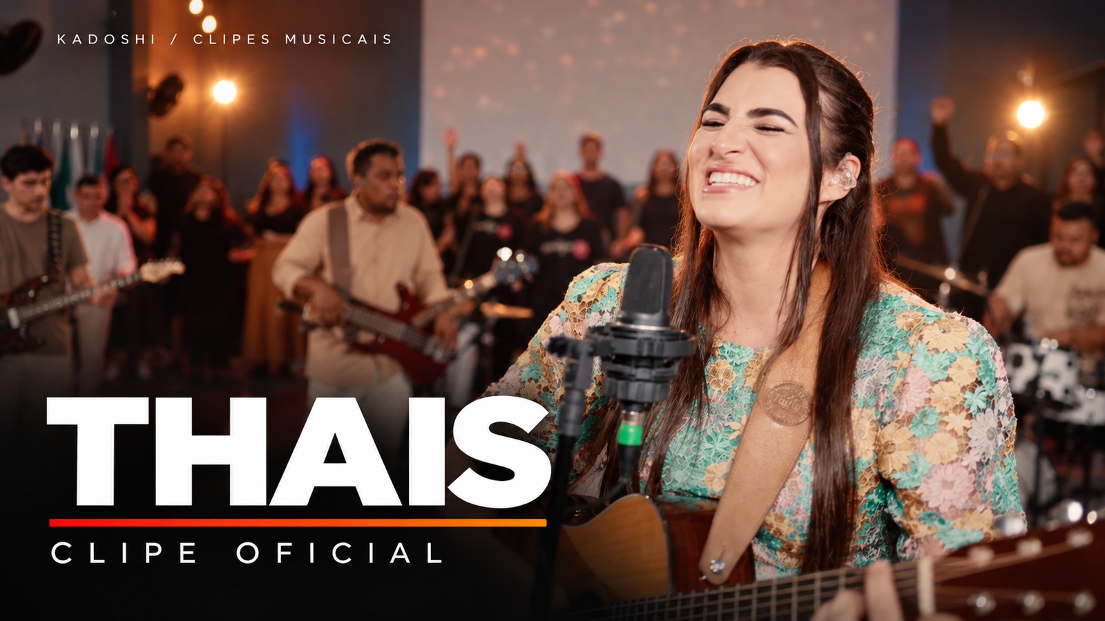 Capa do clipe de Thais, cantando com violão e banda, em composição com a identidade Kadoshi